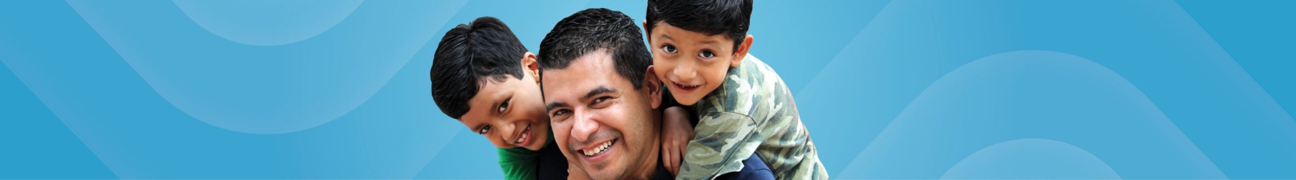 A man and two young boys smiling and hugging.